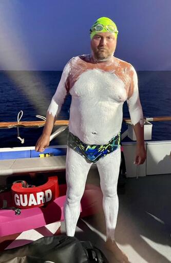 Stève Stievenart's "dad bod", ready to swim, in swimsuit, covered with white cream, on a boat. (by D. Michel for L'Equipe)